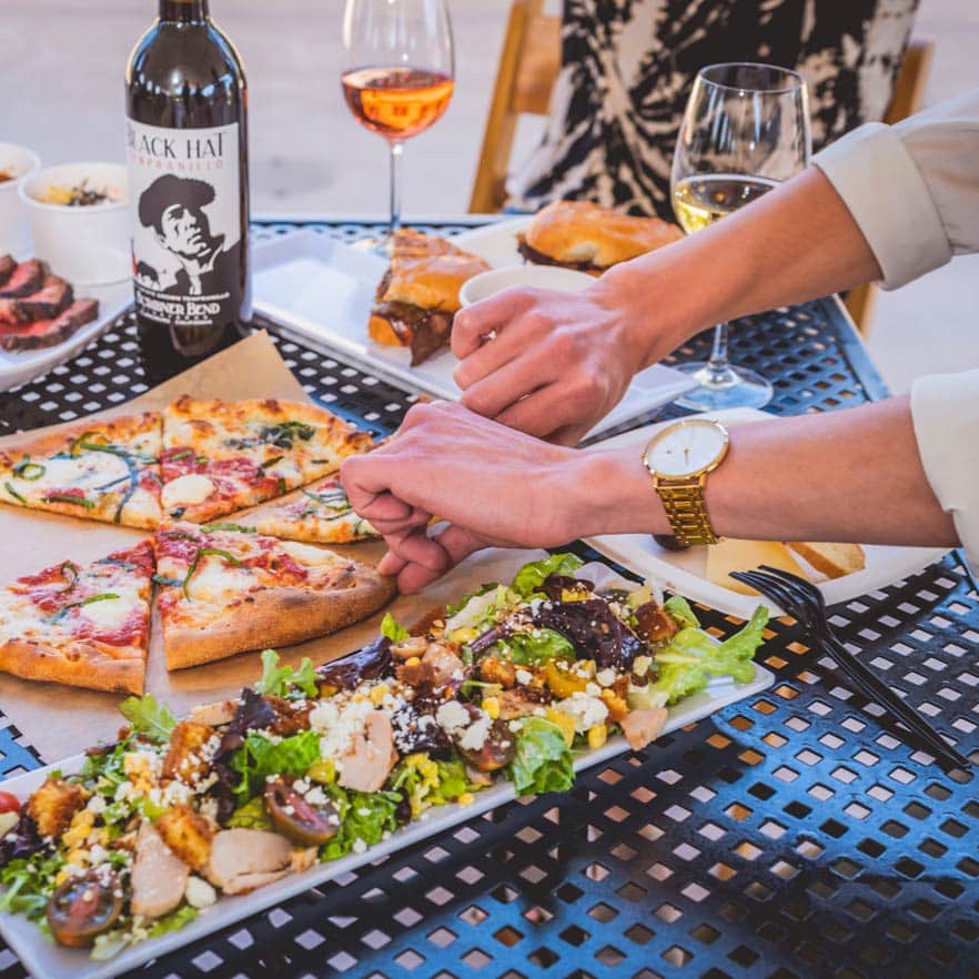 Guests gather around a courtyard table for a casual lunch of wood-fired pizza and appetizers to go with their wine.