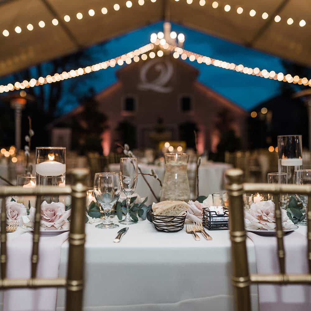 A view from the couples head tables with market lights seen below the covered tent and the 1918 barn with the couples initials lit up on the barn.