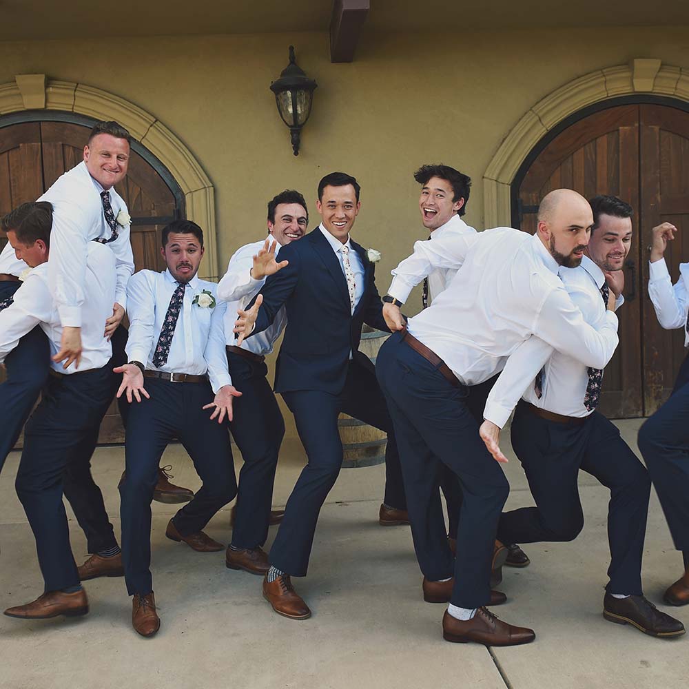 A group of groomsmen and the groom take a fun photo with all different poses during the cocktail hour.
