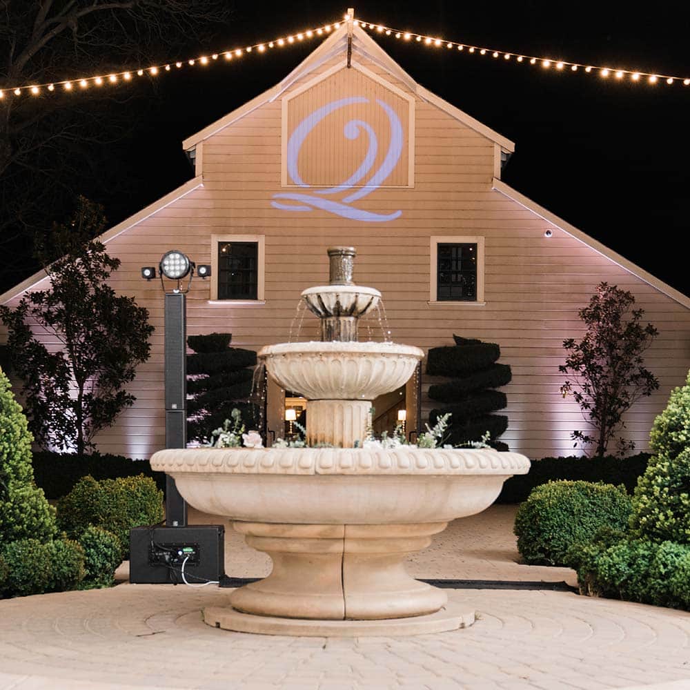 The 1918 barn lit up with the couples last name initial as market lights drop from the highest point of the barn which has a 3 tiered fountain directly in front of it.