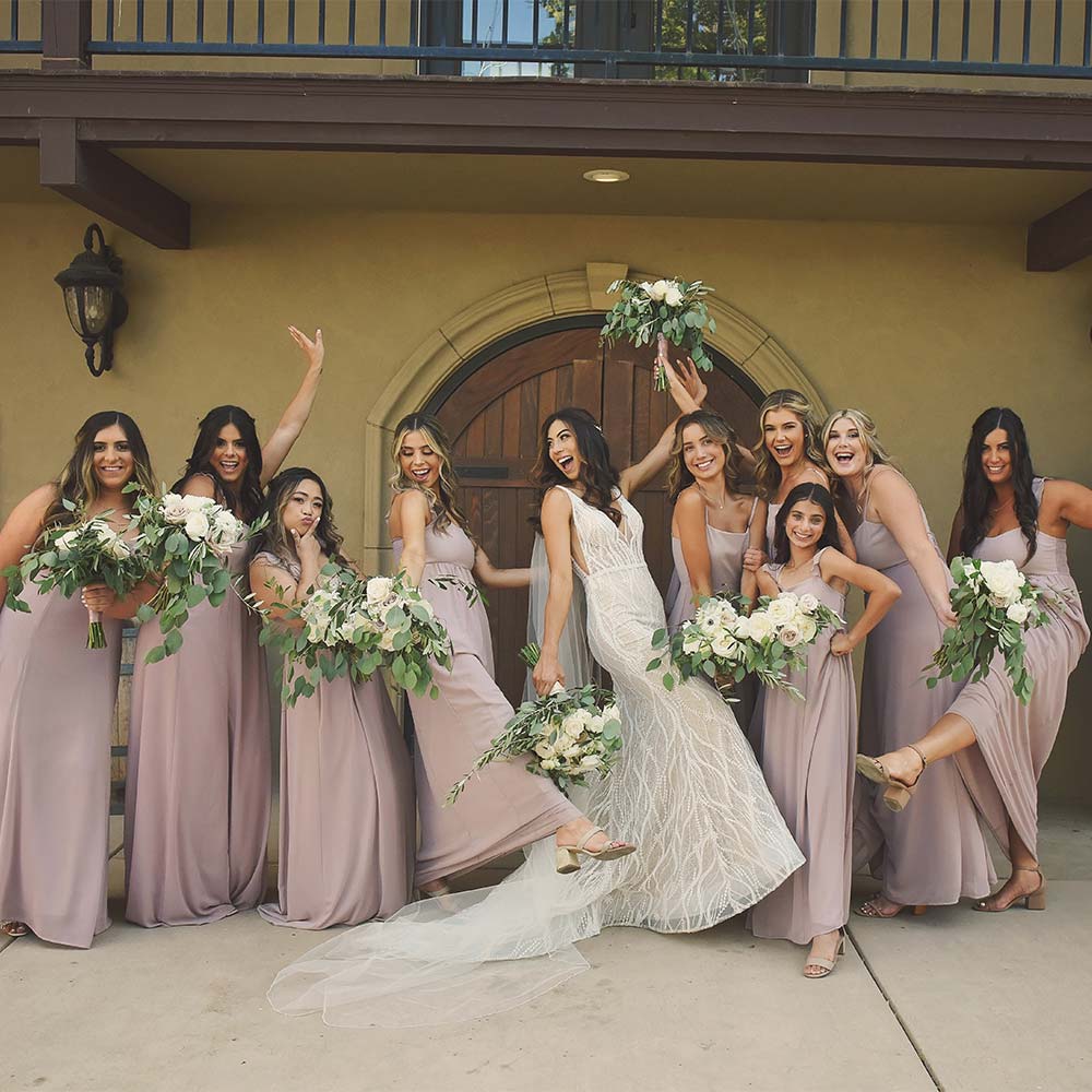 A silly group photos of a bride and her bridesmaids and they all do a fun pose in front of the double doors in the back courtyard.