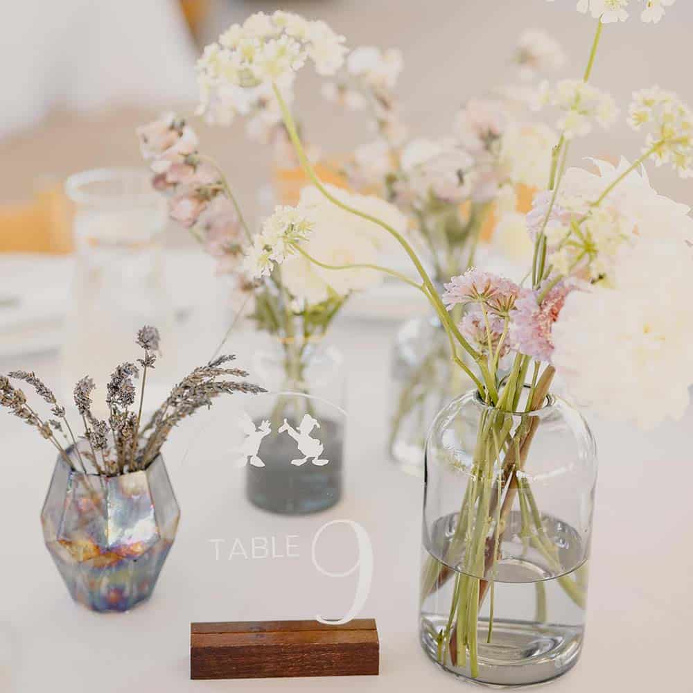 A close up of the small bud vases as decor for Table 9 which has small white, light pink and lavender wild flowers in the vases at this outdoor winery wedding.