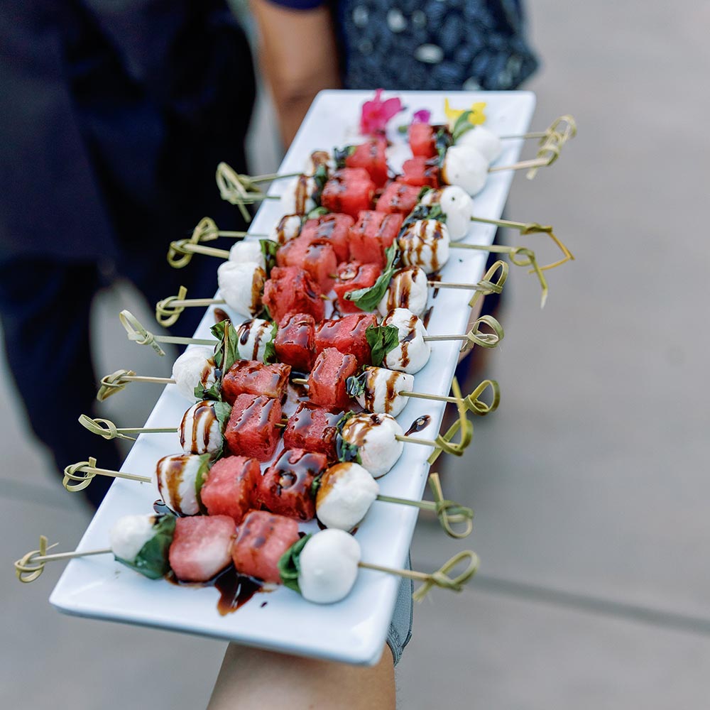 A server holds out of white tray full of appetizers for guests.
