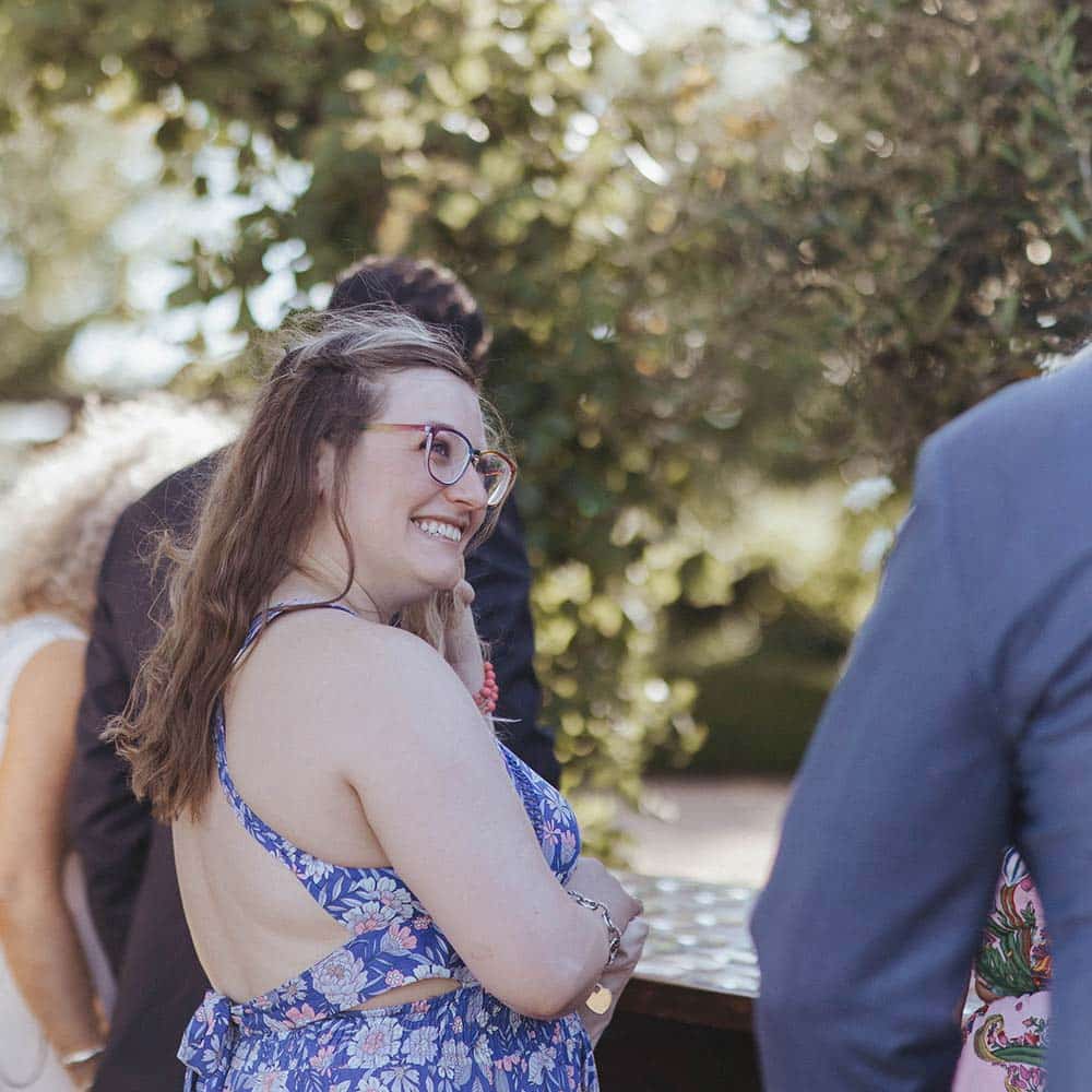 A young lady smiles as she glances toward a young gentleman at an outdoor event.